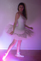 Ballerina with long legs posing in blue violet light