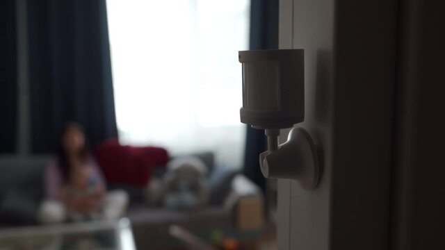 Smart home wireless motion sensor installed on the wall of the living room, motion detector used to detect activities like movement and control smart lights. High quality 4k footage