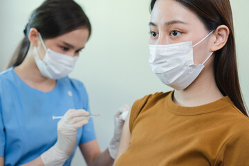 Woman wearing mask is getting vaccinated by a doctor to prevent infection. During outbreak of COVID-19. Female was vaccinated against influenza virus infection.