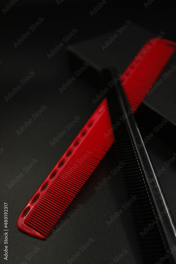 Wall mural two flat combs from a professional hairdressing set lie on a black background