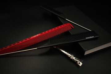 two combs with a metal handle, a red plastic comb and a shiny hairpin dissolve on a black background