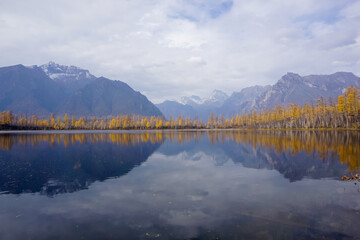 Mountain lake in the taiga and Kodar ridge