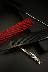 two combs with a metal handle, a red plastic comb and a shiny hairpin dissolve on a black background