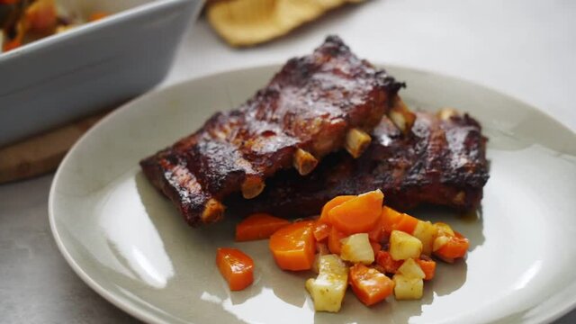 Crop person serving ribs with vegetables