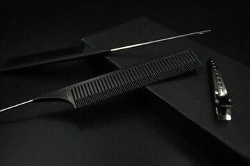 two black flat combs and a metallic shiny hairpin lies on a black background