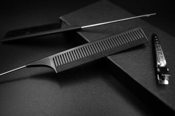 two black flat combs and a metallic shiny hairpin lies on a black background