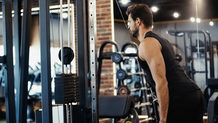 Fototapeta na wymiar strong sportsman exercising on fitness machine in sports center.