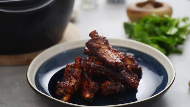 Crop person putting fried ribs on plate