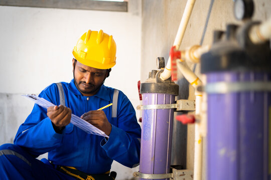 young indian plumber or repairman noting water level at under construction building - concept of professional occupation, and maintenance service.