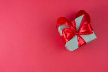 Gift box with red bow on red background. Festive background. Copy space.