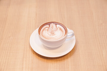 Cute leaf latte hot coffee in white cup on wood table, read to serve.