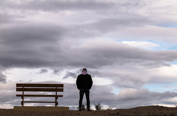 Rear view of man standing next to bench against cloudy Sky. Almeria, Spain