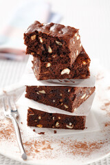 closed up stacked brownies separated by baking parchment on white background .