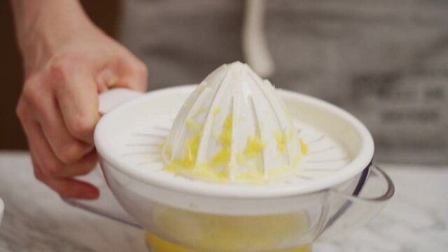 Person squeezing orange juice in juicer in kitchen
