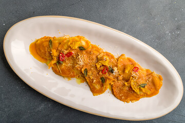 orange ravioli with pumpkin on grey concrete table top view