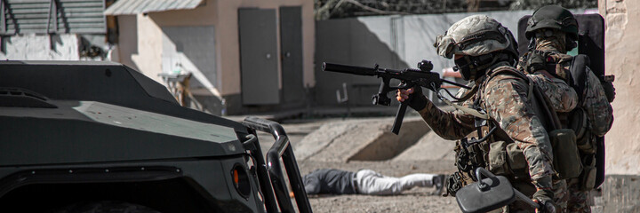 Special Forces on a mission. Hostilities. Military peacekeepers with machine guns repulse the attack of the invaders, hold the defense, capture the terrorists. Long banner.