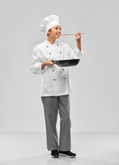 food cooking, culinary and people concept - happy smiling female chef with frying pan and spoon over grey background