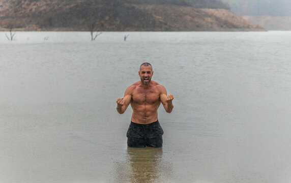 Muscular shirtless man screaming in water