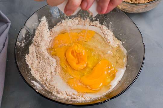 Anonymous person breaking egg into ingredients for keto muffins