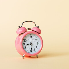 Pink alarm clock on a yellow background. Copy space.