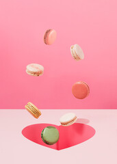 Abstract confectioners concept with colorful macaroon cookies and heart-shaped hole on a pastel pink background. Minimal greeting card or gift card for Valentine’s Day, Women’s Day or wedding.