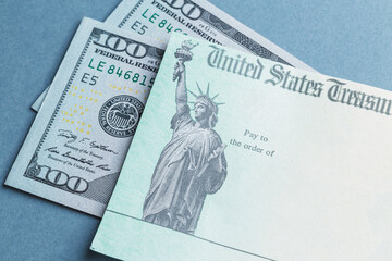 A tax return stimulus check with some American hundred dollar bills - obrazy, fototapety, plakaty