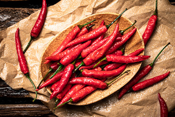Fototapeta Hot chili peppers on a wooden plate. On a wooden background. High quality photo obraz