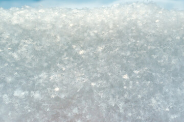 Snowflakes glow in the sun, on fluffy snow, on a frosty winter day. Copy space. Abstract background. 