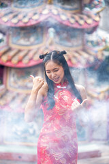Happy Asian girl wearing red traditional Chinese cheongsam decoration at Chinese shrine for Chinese New Year Festival