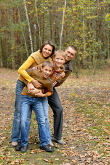 Portrait of family of four posing in autumn forest