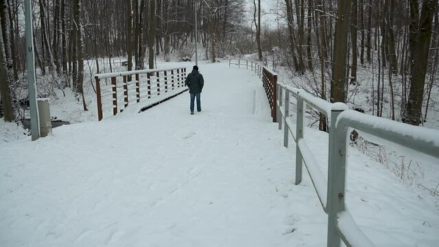 unidentified man walks over a bridge during winter in Gorowo, Bartoszyce County, Warmian-Masurian Voivodeship, Poland. activities in winter and snow