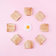 Circle of toast bread with an fried egg in the middle on a pastel pink background. Breakfast minimal concept. Fried egg mood. Tasty meal wallpaper. Flat lay. Organic healthy food.