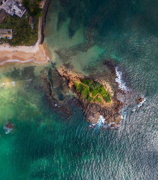 Scenic view of Parrot rock - small island along the Mirissa Beach in Sri Lanka. Braking waves Top view aerial photo from flying drone. Traveling and exotic countries concept.