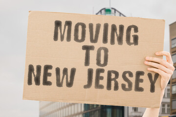 The phrase " Moving to New Jersey " on a banner in men's hand with blurred sea on the background. Relocation. Beach. Sun. Relax. Warm. Apartment. Relocating. Traveler