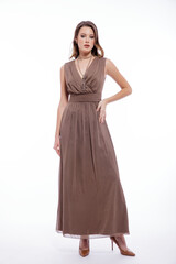 High fashion photo of beautiful elegant young woman in a pretty beige brown dress with a neckline, necklace posing on white background. Slim figure, make up,  luxurious hair, shiny curls. Studio Shot