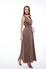 Fototapeta premium High fashion photo of beautiful elegant young woman in a pretty beige brown dress with a neckline, necklace posing on white background. Slim figure, make up, luxurious hair, shiny curls. Studio Shot
