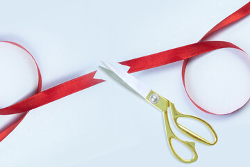 Grand opening, Gold scissors cutting red silk ribbon against White background, Top view, banner, copy space.