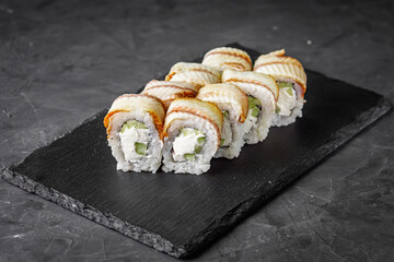 appetizing Philadelphia sushi roll with eel and cucumber on a black stone plate