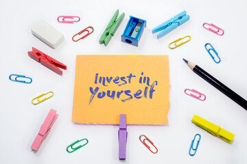 Invest in yourself written on Set of colorful paper clips with white copy space background