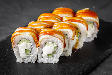 appetizing Philadelphia sushi roll with eel and cucumber on a black stone plate