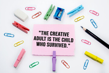  The creative adult is the child that has survived written on Set of colorful paper clips with white copy space background.