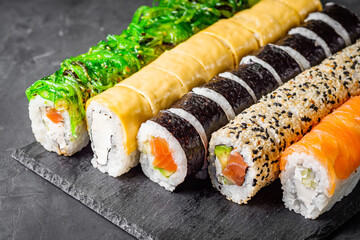 appetizing set of sushi roll on a black stone plate