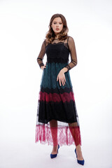 High fashion photo of a beautiful elegant young woman in a pretty triple black, red, green color dress with lace, blue shoes posing on white background. Slim figure, hair, shiny curls. Studio Shot