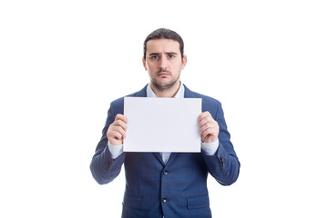 Upset businessman holding a blank paper sheet with copy space, looking sad and disappointed to camera, isolated on white background - 480205161