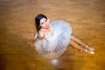 Ballerina in a white tutu on the floor looking up
