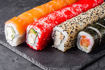 appetizing set of sushi roll on a black stone plate