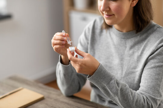 medicine, quarantine and pandemic concept - close up of woman making self testing coronavirus test at home