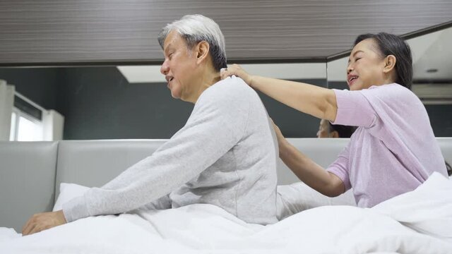 Senior woman massaging backbone of husband on bed