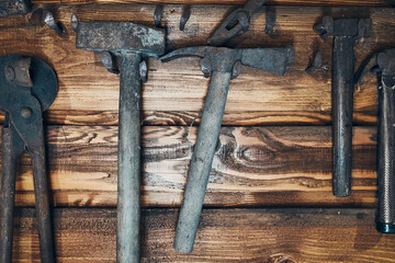 Old rusty blacksmith tools hung on wooden wall