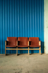 three old leather armchairs, covered with brown leather, against a blue wall in a vertical format